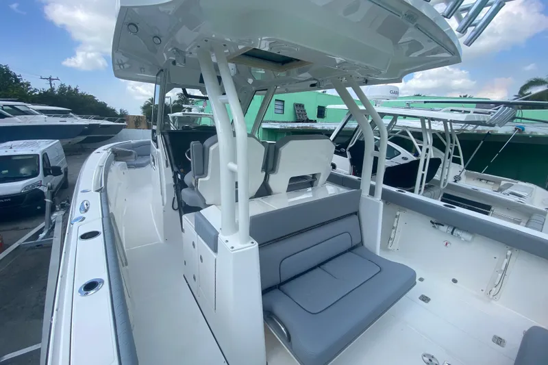 Slide: The Image of 2019 Pursuit S 328 Sport boat interior with seating and helm station, docked outdoors. - 19