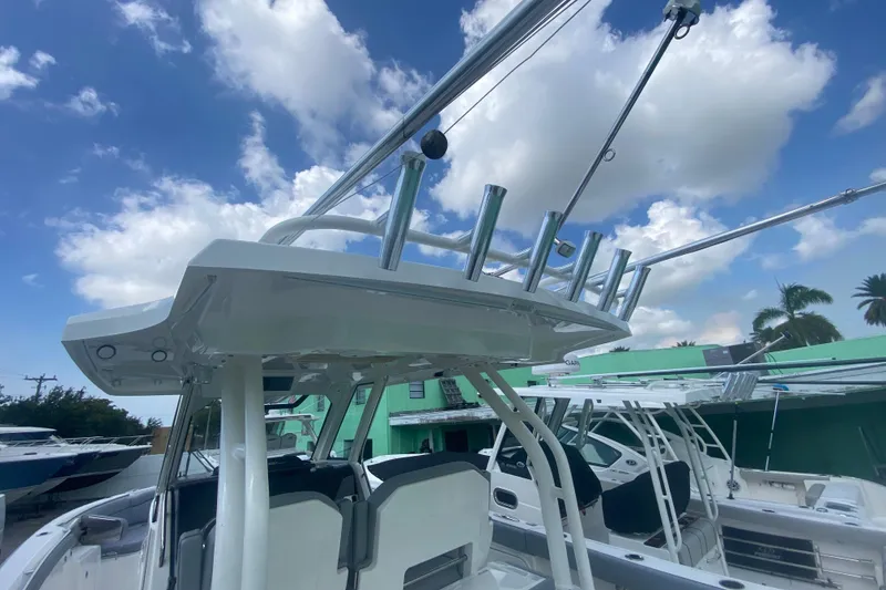 Slide: The Image of 2019 Pursuit S 328 Sport boat with rod holders under a blue sky. - 18