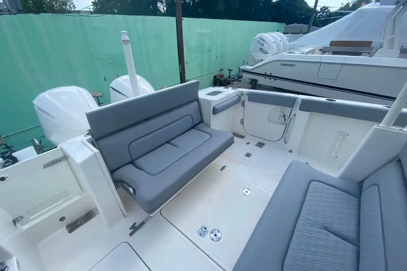 Slide: The Image of 2019 Pursuit S 328 Sport boat interior with gray seating and dual outboard engines. - 12