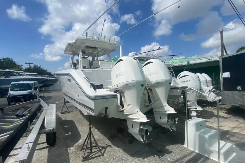 Slide: The Image of 2019 Pursuit S 328 Sport boat with twin Yamaha outboard engines, parked outdoors under a blue sky. - 2