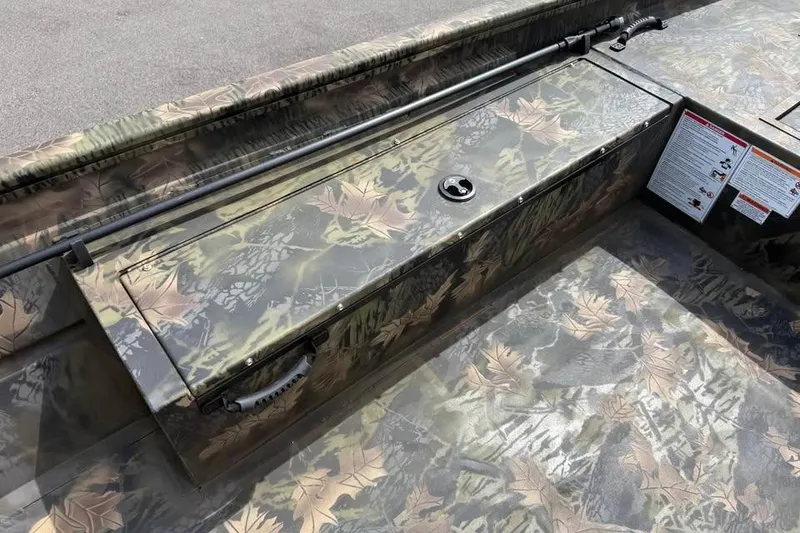 Slide: The Image of 2027 Crestliner 1760 Retriever Jon boat with camouflage design and storage compartment. - 11