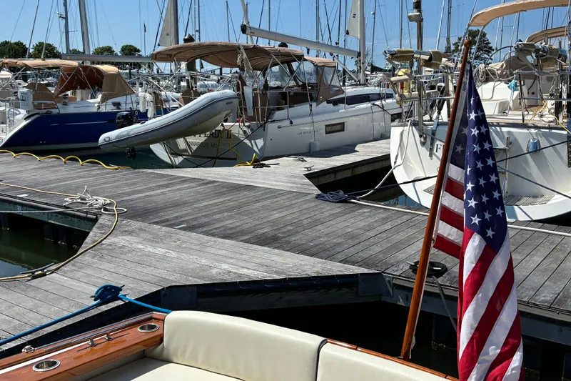 Slide: The Image of Docked boats at marina with American flag, featuring a 2000 Little Harbor WhisperJet 40. - 6