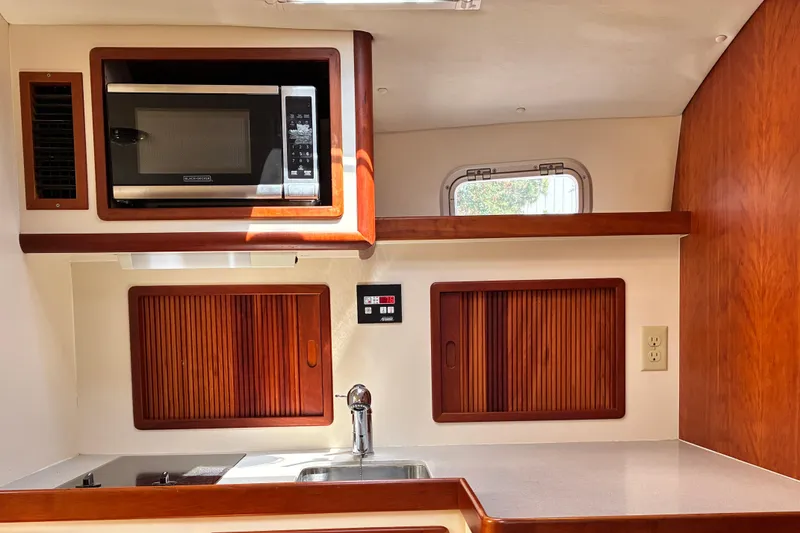 Slide: The Image of Little Harbor WhisperJet 40 (2000) yacht kitchen with microwave, sink, and wooden cabinets. - 26