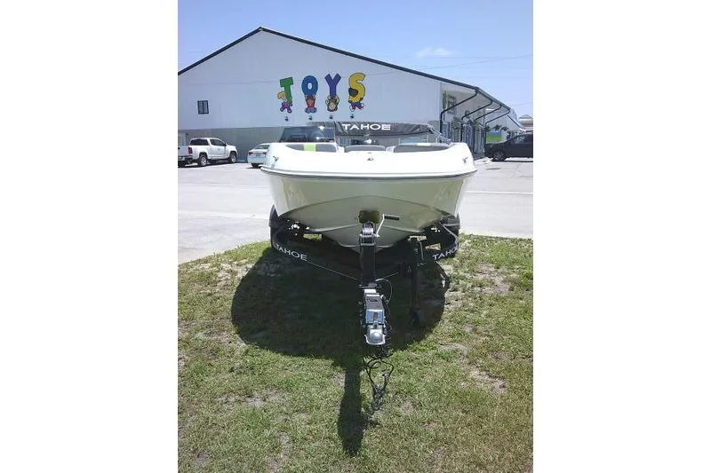 Slide: The Image of 2022 Tahoe T16 boat on trailer, parked outside a building with "TOYS" sign. - 6