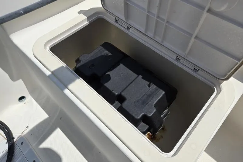 Slide: The Image of Open storage compartment on a 2000 May-Craft 2000CC boat, featuring a black battery box. - 17