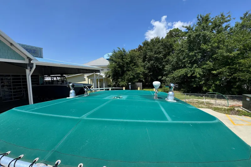 Slide: The Image of 2000 Stamas 250 Tarpon boat with green cover, parked outdoors under clear blue sky. - 25