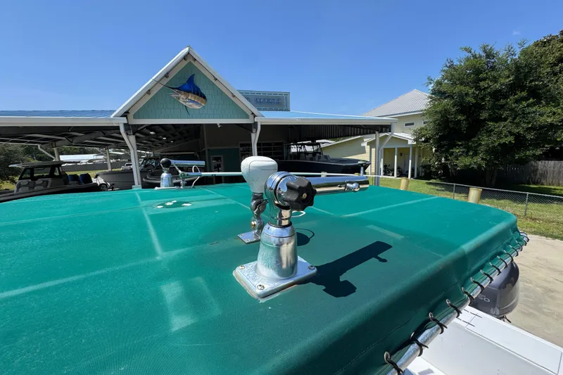 Slide: The Image of 2000 Stamas 250 Tarpon boat with green cover, docked near a marina building. - 26