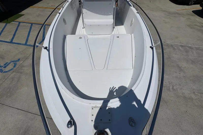 Slide: The Image of 2000 Stamas 250 Tarpon boat deck, white interior, shadow visible, parked on concrete. - 22
