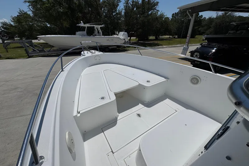 Slide: The Image of 2000 Stamas 250 Tarpon boat interior with seating and storage, parked outdoors. - 20