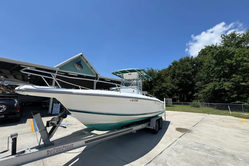 Slide: The Image of 2000 Stamas 250 Tarpon boat on trailer, parked outdoors under clear blue sky. - 4