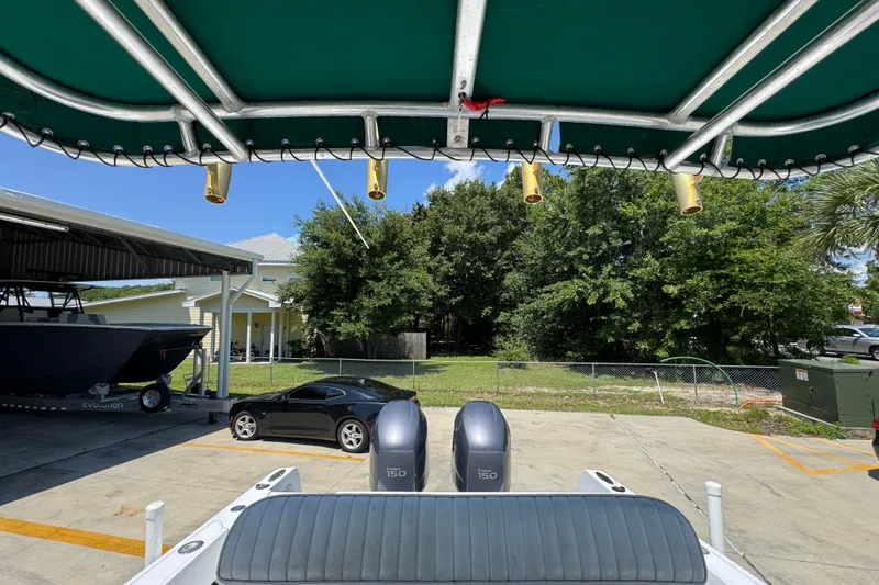 Slide: The Image of 2000 Stamas 250 Tarpon boat with dual engines, parked near a black car and trees. - 34