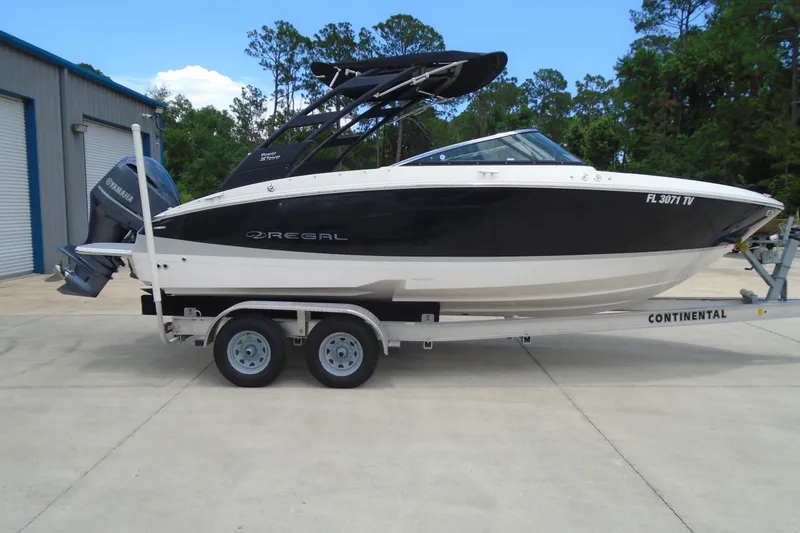 The Image of 2024 Regal LX4 boat on trailer, parked outdoors near a building. - 0