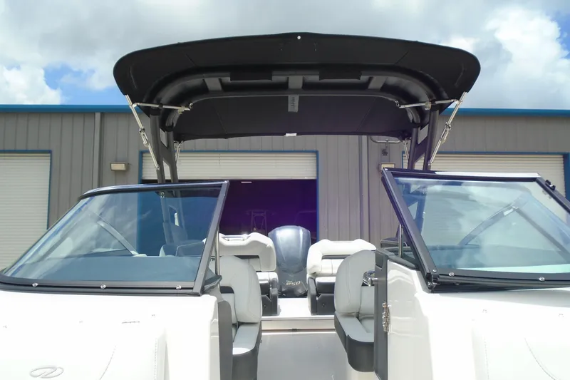 Slide: The Image of 2024 Regal LX4 boat with open cockpit and canopy, parked outside a warehouse. - 8