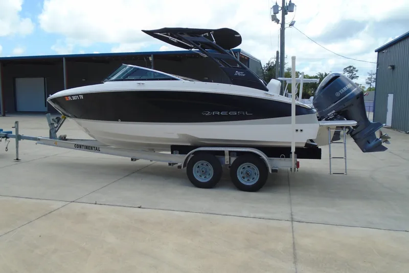 Slide: The Image of 2024 Regal LX4 boat on trailer, black and white design, parked outdoors. - 2
