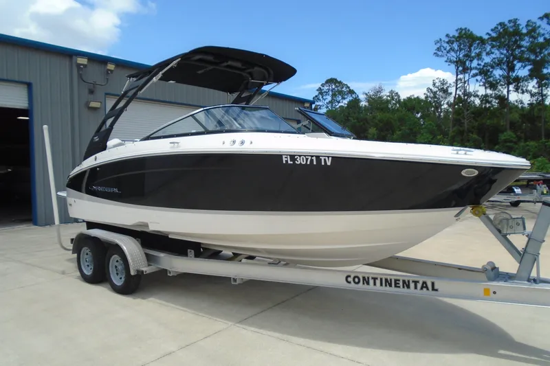 Slide: The Image of 2024 Regal LX4 boat on trailer, parked outside a warehouse. - 1