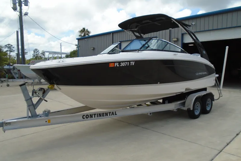 Slide: The Image of 2024 Regal LX4 boat on trailer, parked outside a warehouse. - 4