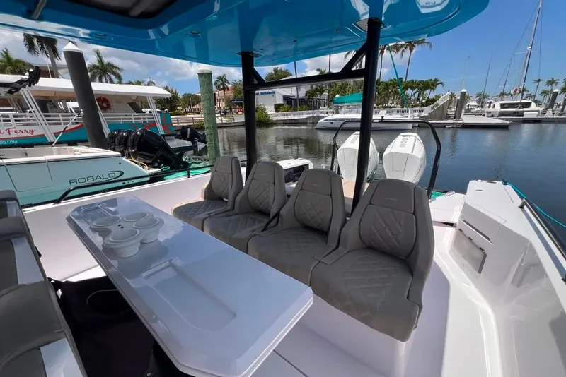 Slide: The Image of 2023 Axopar Brabus 37 Sun-Top boat interior with seating and table, docked at marina. - 55