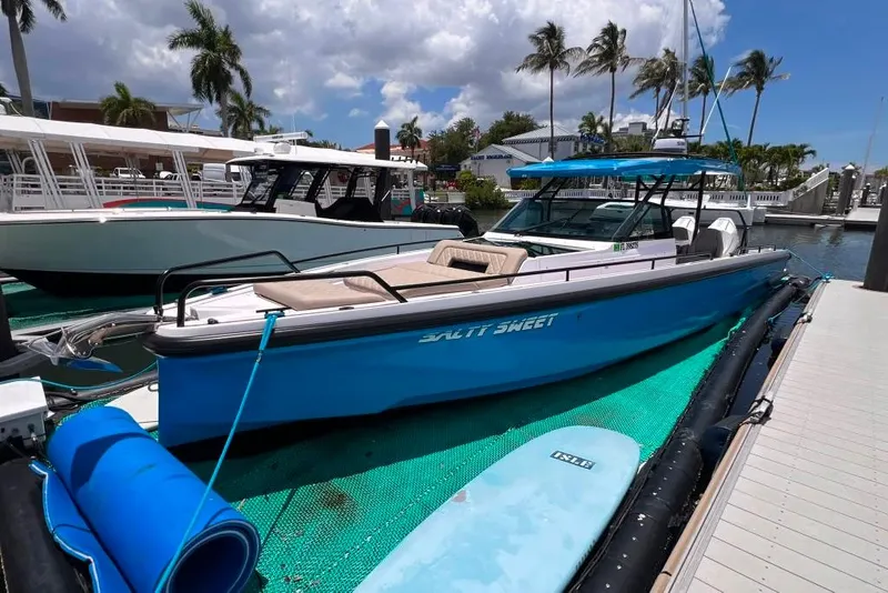Slide: The Image of 2023 Axopar Brabus 37 Sun-Top boat docked, featuring a sleek blue design and spacious deck. - 5