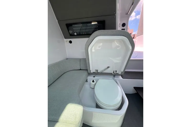 Slide: The Image of 2023 Axopar Brabus 37 Sun-Top interior with compact toilet and seating area. - 10