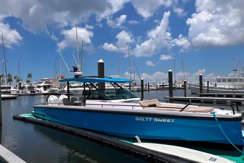 Slide: The Image of 2023 Axopar Brabus 37 Sun-Top boat docked at marina under blue sky. - 2