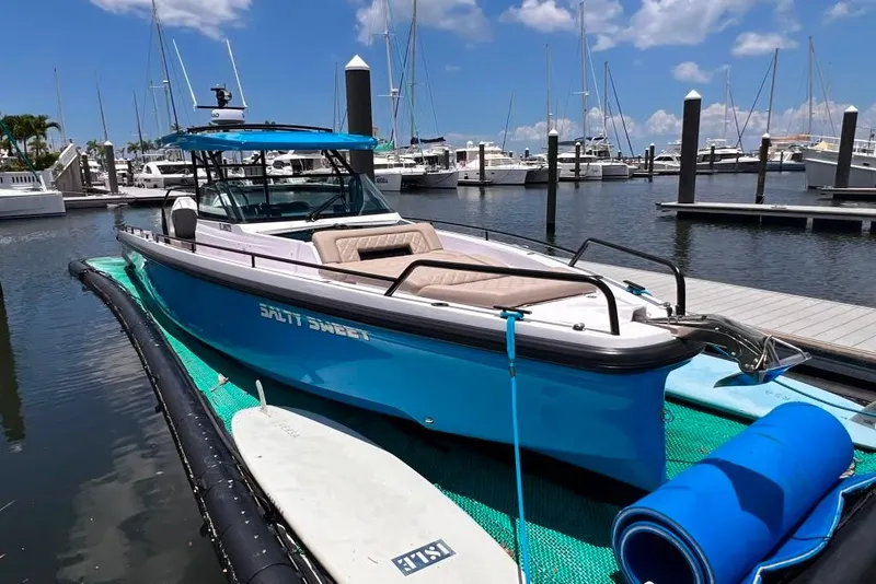 Slide: The Image of 2023 Axopar Brabus 37 Sun-Top boat docked in a marina under a clear sky. - 3