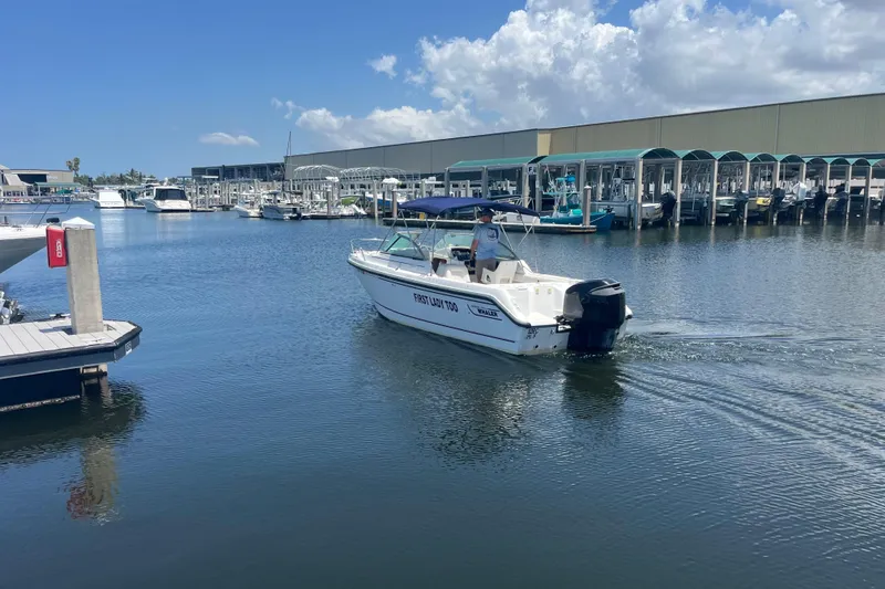 Slide: The Image of 2003 Boston Whaler 210 Ventura boat cruising in a marina under a clear blue sky. - 18