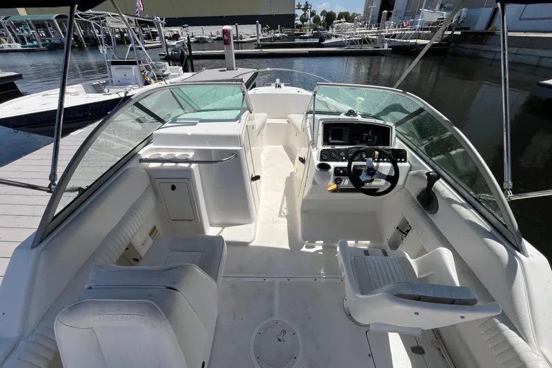 Slide: The Image of 2003 Boston Whaler 210 Ventura boat interior at marina, featuring helm and seating area. - 12