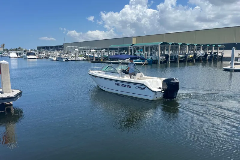 Slide: The Image of 2003 Boston Whaler 210 Ventura boat cruising in a marina under a clear blue sky. - 1