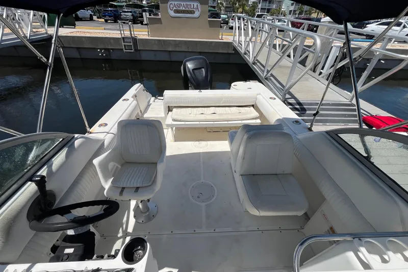 Slide: The Image of 2003 Boston Whaler 210 Ventura boat interior at dock, featuring seating and steering wheel. - 14