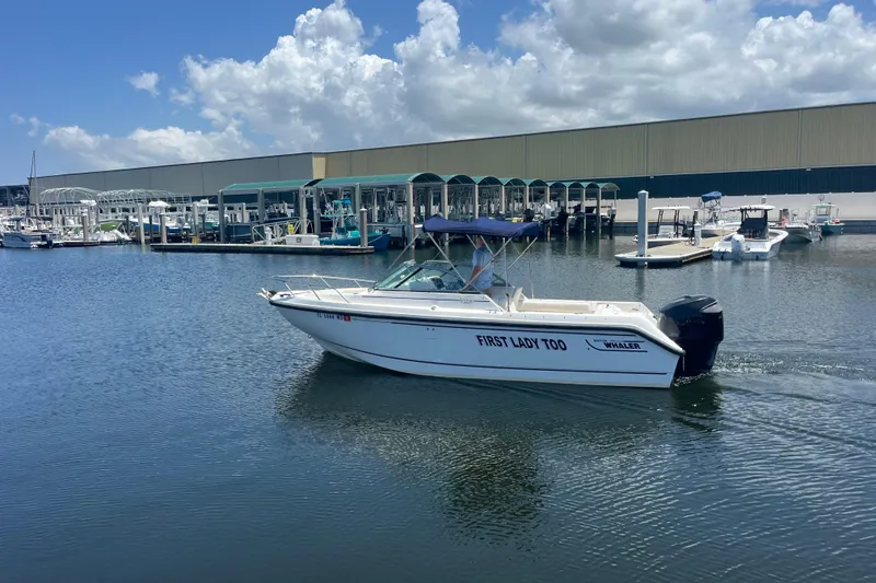 The Image of 2003 Boston Whaler 210 Ventura boat named "First Lady Too" cruising in a marina. - 0