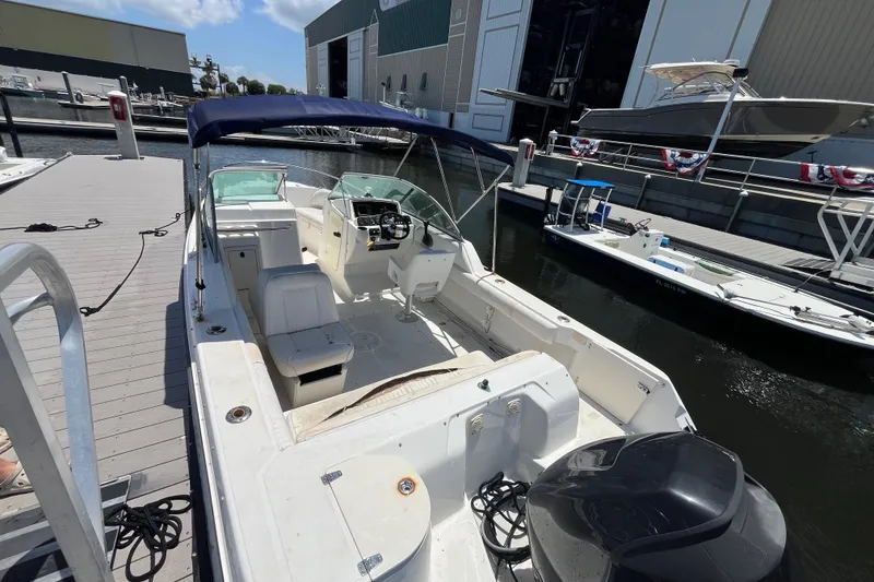 Slide: The Image of 2003 Boston Whaler 210 Ventura boat docked at marina, featuring spacious seating and canopy. - 9
