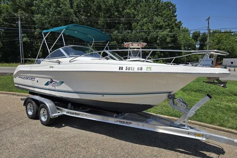 Slide: The Image of 2004 Aquasport 215 Osprey Sport boat on trailer, parked outdoors. - 13