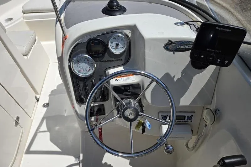 Slide: The Image of 2004 Aquasport 215 Osprey Sport boat dashboard with steering wheel and gauges. - 19