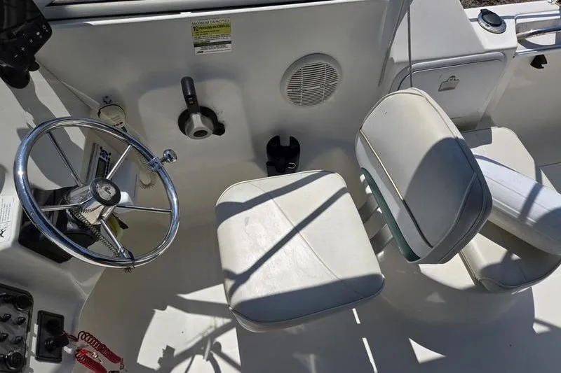 Slide: The Image of 2004 Aquasport 215 Osprey Sport boat interior with steering wheel and seating. - 10