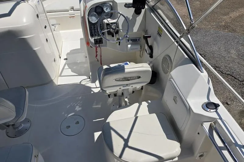 Slide: The Image of 2004 Aquasport 215 Osprey Sport boat interior with steering wheel and seating. - 11