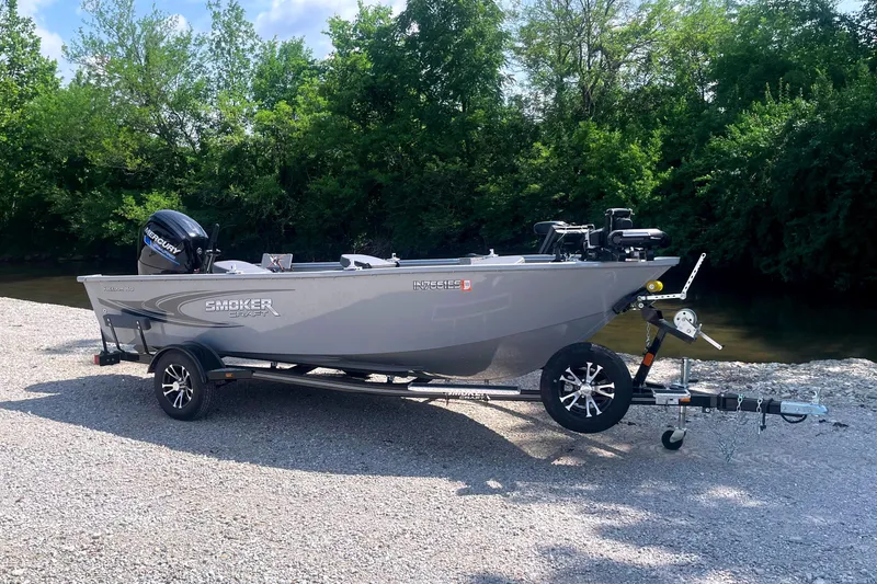 The Image of A gray boat on a trailer by a riverbank, surrounded by trees. - 0