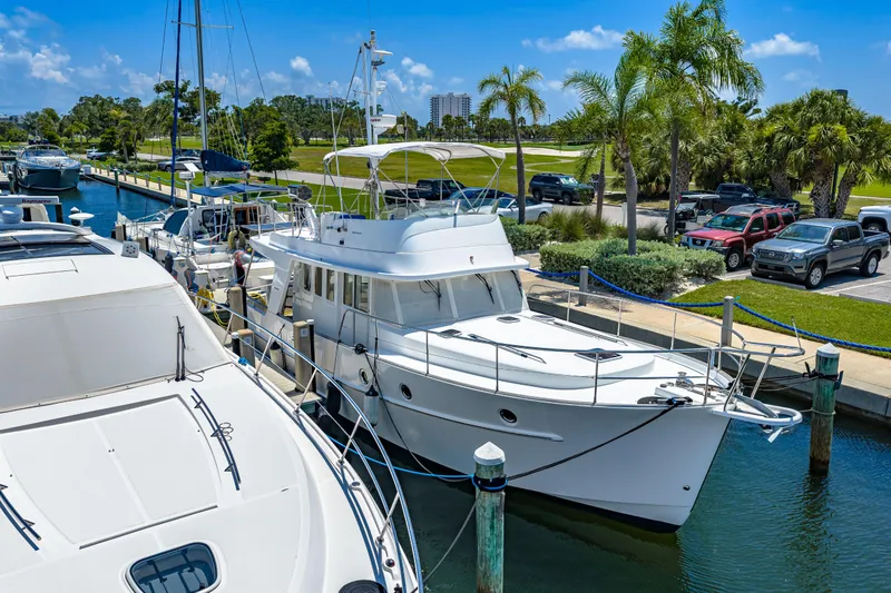 Slide: The Image of 2006 Beneteau Swift Trawler 42 docked at marina, surrounded by palm trees and parked cars. - 7