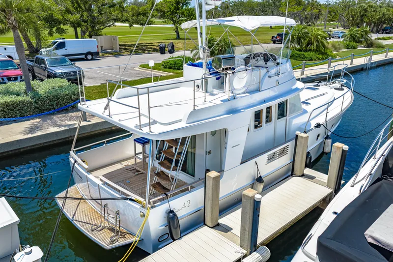 Slide: The Image of 2006 Beneteau Swift Trawler 42 docked at marina, showcasing sleek design and spacious deck. - 12