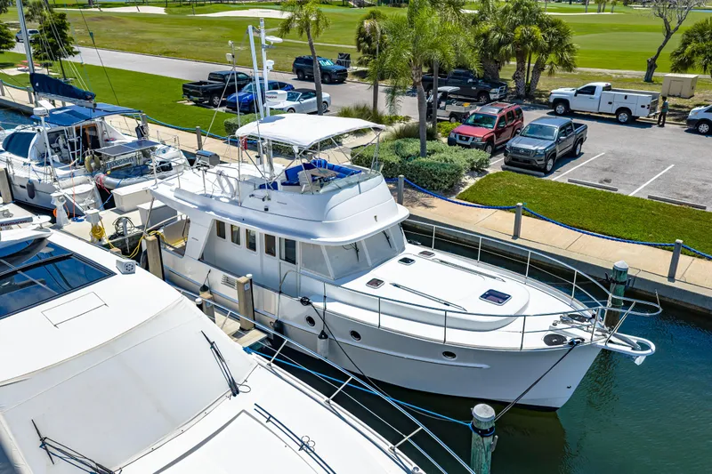 Slide: The Image of 2006 Beneteau Swift Trawler 42 docked at marina, surrounded by other boats and parked vehicles. - 8