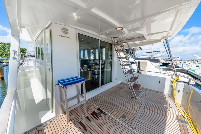 Slide: The Image of 2006 Beneteau Swift Trawler 42 yacht deck with ladder and seating, docked at marina. - 38