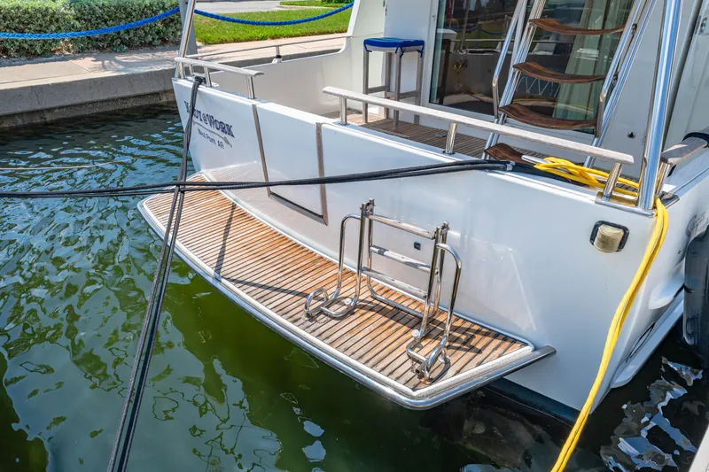 Slide: The Image of 2006 Beneteau Swift Trawler 42 docked, featuring a wooden swim platform and stainless steel ladder. - 32