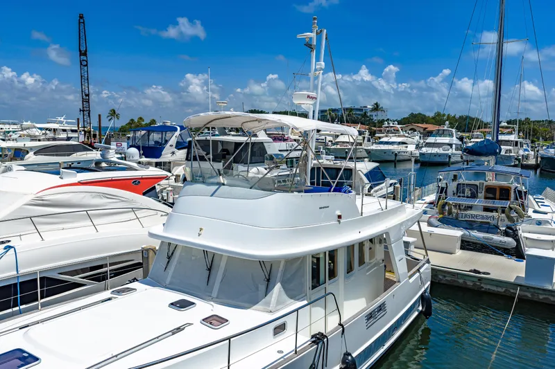 Slide: The Image of 2006 Beneteau Swift Trawler 42 docked in a sunny marina, surrounded by other boats. - 20
