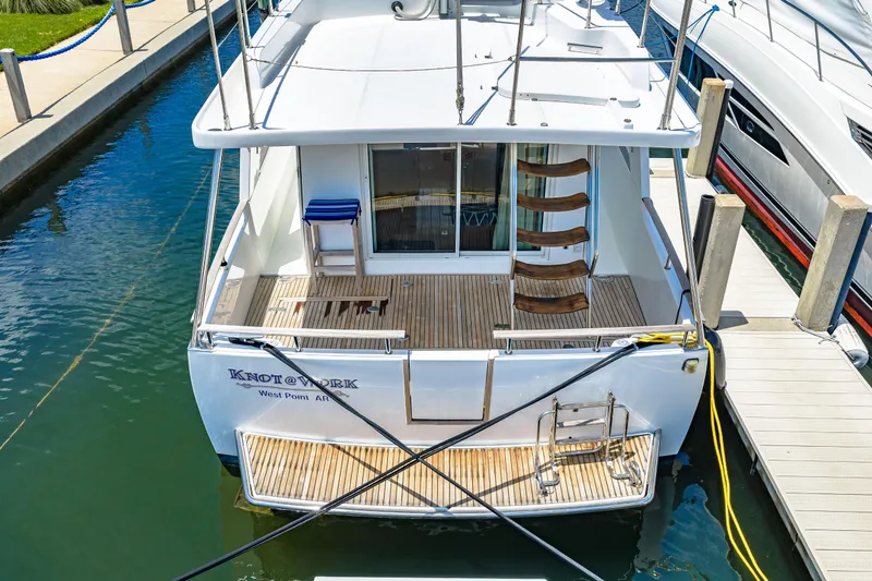 Slide: The Image of 2006 Beneteau Swift Trawler 42 docked, rear view with wooden deck and ladder. - 16