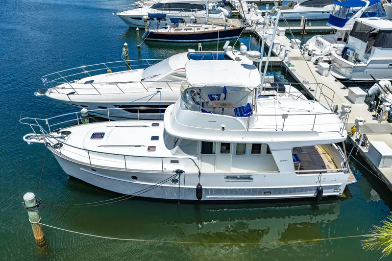 Slide: The Image of 2006 Beneteau Swift Trawler 42 docked at marina, showcasing sleek design and spacious deck. - 4