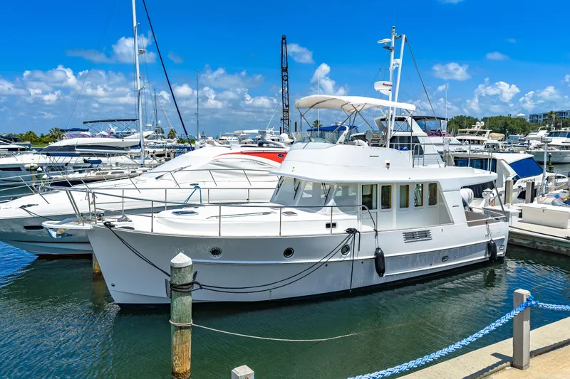 Slide: The Image of 2006 Beneteau Swift Trawler 42 docked at a marina under a clear blue sky. - 2