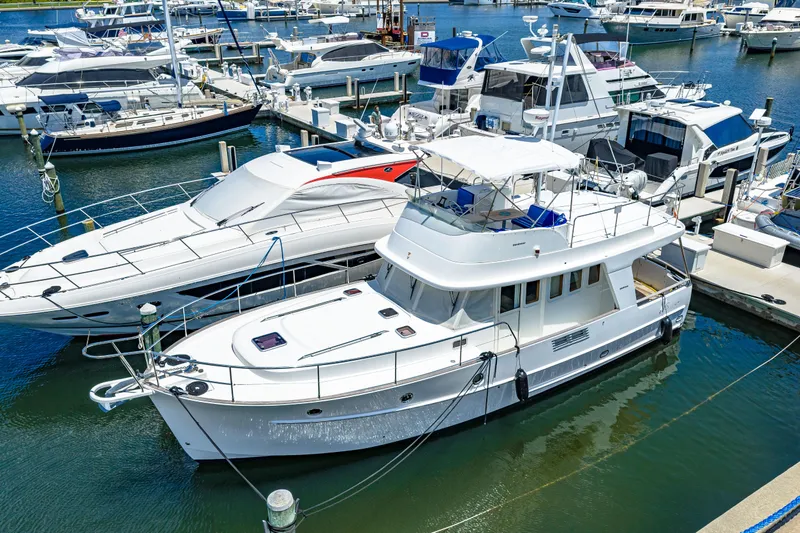 Slide: The Image of 2006 Beneteau Swift Trawler 42 docked at a marina, surrounded by other boats. - 5