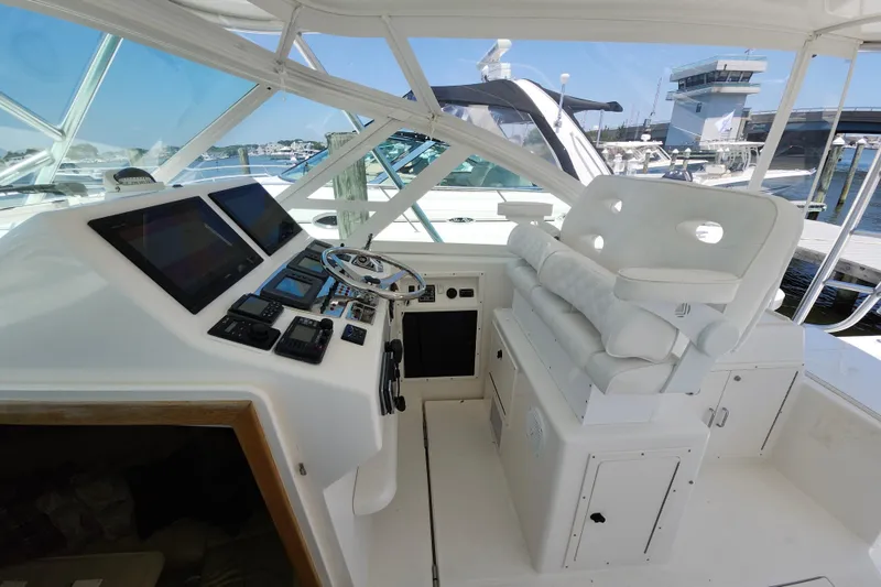 Slide: The Image of 2009 Cabo 36 Express helm with modern controls and plush seating at marina. - 9