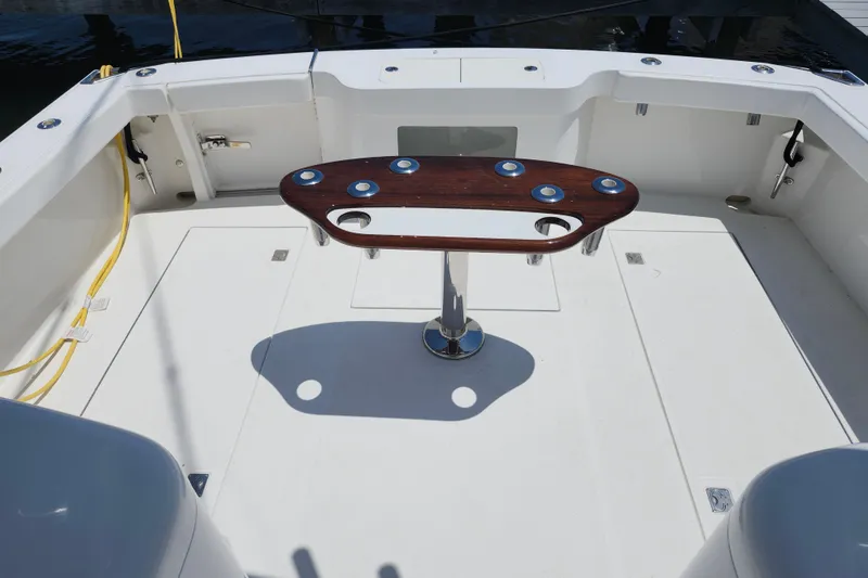 Slide: The Image of 2009 Cabo 36 Express boat deck with wooden table and fishing rod holders. - 13