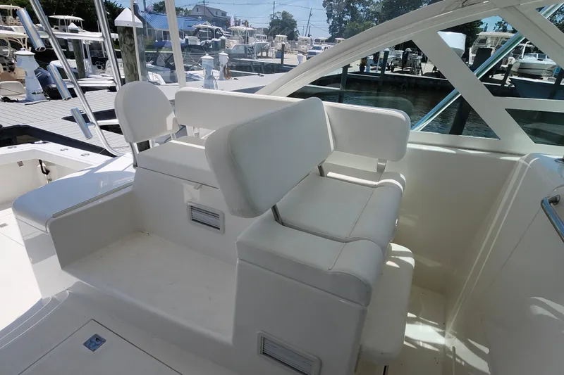 Slide: The Image of 2009 Cabo 36 Express boat seating area with white cushions at marina. - 10