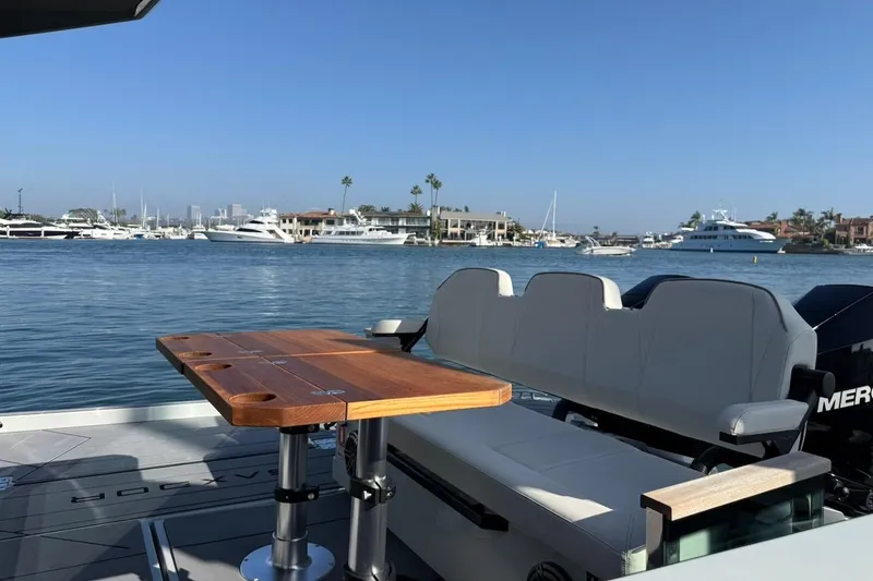 Slide: The Image of 2024 Saxdor 320 GTC boat interior with wooden table, overlooking marina with yachts. - 6